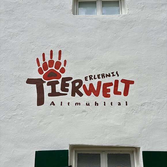 das Logo der Erlebnistierwelt Altmühltal ist auf einer Hauswand zu sehen. Das Logo hat die Farben Rot und Braun